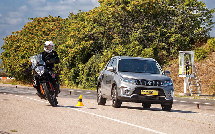 Ein Auto und ein Motorrad fahren auf der Übungsstrecke im Fahrtechnikzentrum