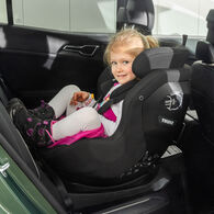 OEAMTC-Kindersitztest-Fruehjahr-2025 (2) Ein kleines Mädchen mit blonden Haaren sitzt beim Kindersitztest in einem rückwärtsgerichteten Kindersitz auf der Rückbank eines Autos und lächelt.