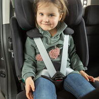 OEAMTC-Kindersitztest-Fruehjahr-2025 (7) Ein kleines Mädchen mit braunen Haaren sitzt im Rahmen des Kindersitztests angeschnallt in einem Kindersitz eines Autos. Sie trägt einen grünen Pullover und blaue Jeans und lächelt.