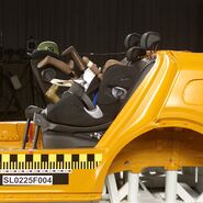 Zwei Kindersitze sind in einem Crashtestauto montiert, das von der Seite zu sehen ist und aprubt bremst.