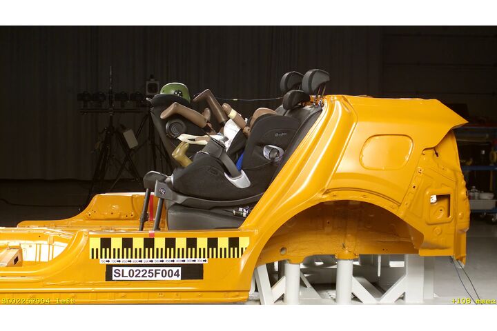 Zwei Kindersitze sind in einem Crashtestauto montiert, das von der Seite zu sehen ist und aprubt bremst.
