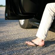 Eine Person steigt mit FlipFlops aus einem Auto aus