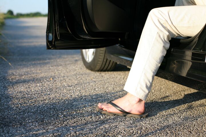 Eine Person steigt mit FlipFlops aus einem Auto aus