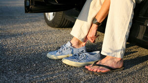 Person wechselt Flip-Flops gegen ein Paar geschlossene, bequeme Sportschuhe.