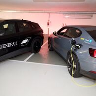 Ein schwarzes und ein graues e-Auto werden in einem Parkhaus geladen. 