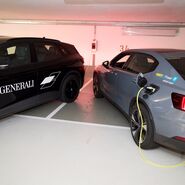 Ein schwarzes und ein graues e-Auto werden in einem Parkhaus geladen. 
