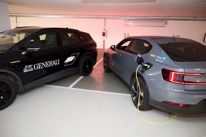 Ein schwarzes und ein graues e-Auto werden in einem Parkhaus geladen. 