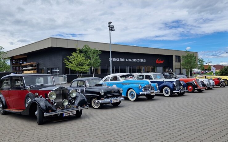 Sieben Oldtimer nebeneinander vor einer Spenglerei.