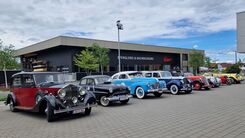 Sieben Oldtimer nebeneinander vor einer Spenglerei.