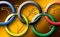 Die Olympischen Ringe vor einer goldenen Weltkarte.