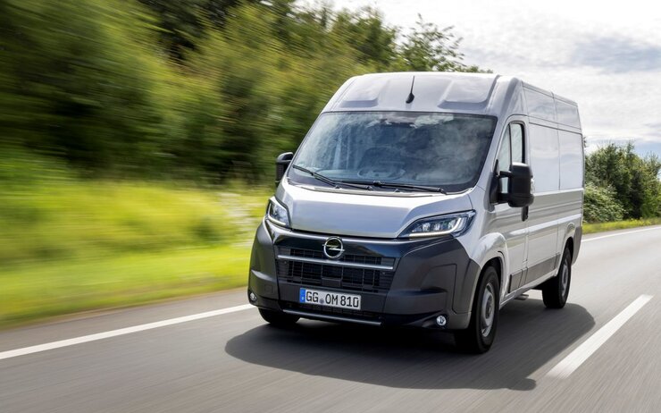 Opel Movano.jpg Das Foto zeigt einen grauen Lieferwagen von Opel der auf einer Landstraße fährt.