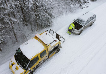 Ein ÖAMTC-Pannenfahrzeug schleppt ein anderes Fahrzeug in winterlicher Landschaft ab