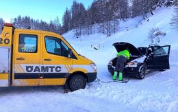 ÖAMTC Pannenfahrzeug auf verschneiter Straße, Pannenfahrer gibt einem Auto Starthilfe.