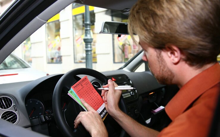 Mann, der im Auto sitzend, einen Parkschein ausfüllt