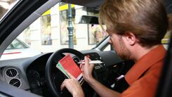 Mann, der im Auto sitzend, einen Parkschein ausfüllt