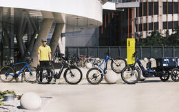 4 Pedelecs stehen vor dem ÖAMTC-Gebäude in Erdberg aufgereiht mit auto touring-Redakteur mit gelben ÖAMTC-Poloshirt und Radhelm.