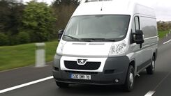 Das Bild zeigt ein weißes Nutzfahrzeug, welches auf einer Landstraße unterwegs ist.