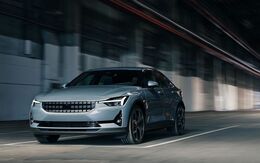 Ein grauer Polestar 2 fährt an einer Asphaltmauer vorbei.