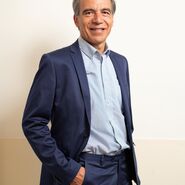 Lächelnder Präsident Günter Thumser im Anzug vor einer Wand