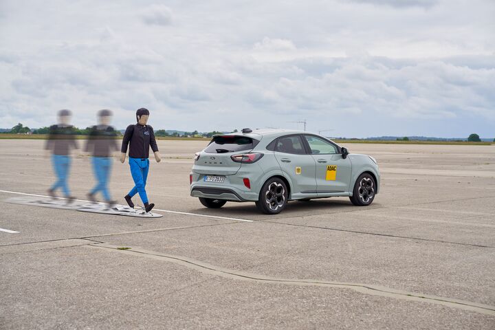Das Bild zeigt einen zu Fuß gehenden Crashtest-Dummy, der sich hinter einem grauen Auto vorbeibewegt. Die Bewegung wird mittels einer Serienaufnahme dargestellt.