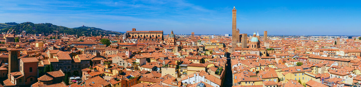 Ein weiter Blick über die Dächer von Bologna, mit den roten Ziegeldächern, den charakteristischen Türmen und den historischen Gebäuden, die die Stadtlandschaft prägen.