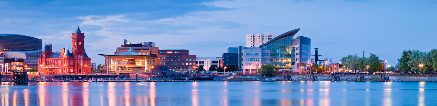 Bei blauer Abenddämmerung verschmelzen die moderne Skyline und historische Gebäude am Cardiff Bay zu einer beeindruckenden städtischen Symphonie.