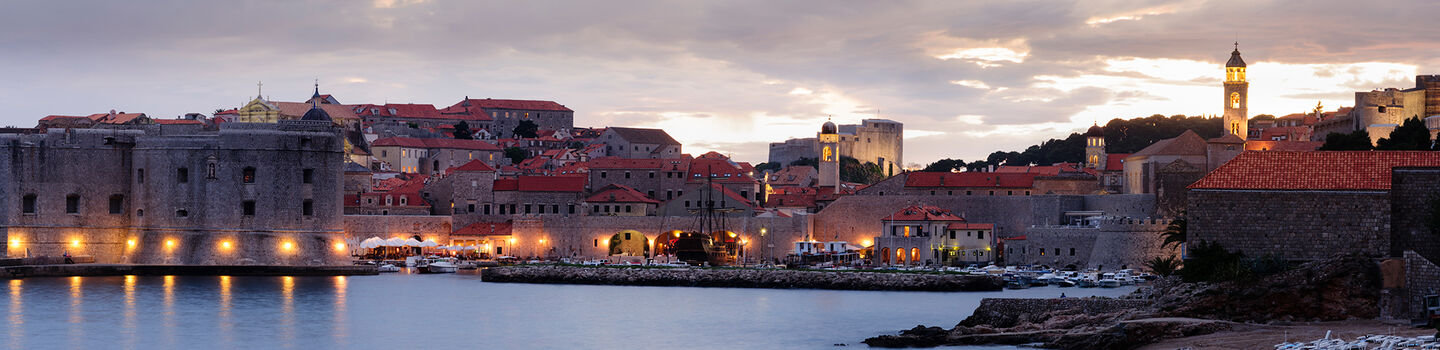 Dubrovnik in der Abenddämmerung, mit den alten Stadtmauern und Gebäuden, die in sanftes, goldenes Licht getaucht sind.