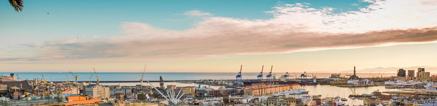Ein atemberaubender Blick von oben auf den Hafen von Genua bei Sonnenuntergang, mit den Schiffen und dem sanften Licht, das den Hafen und die umliegenden Gebäude in goldene Töne taucht.