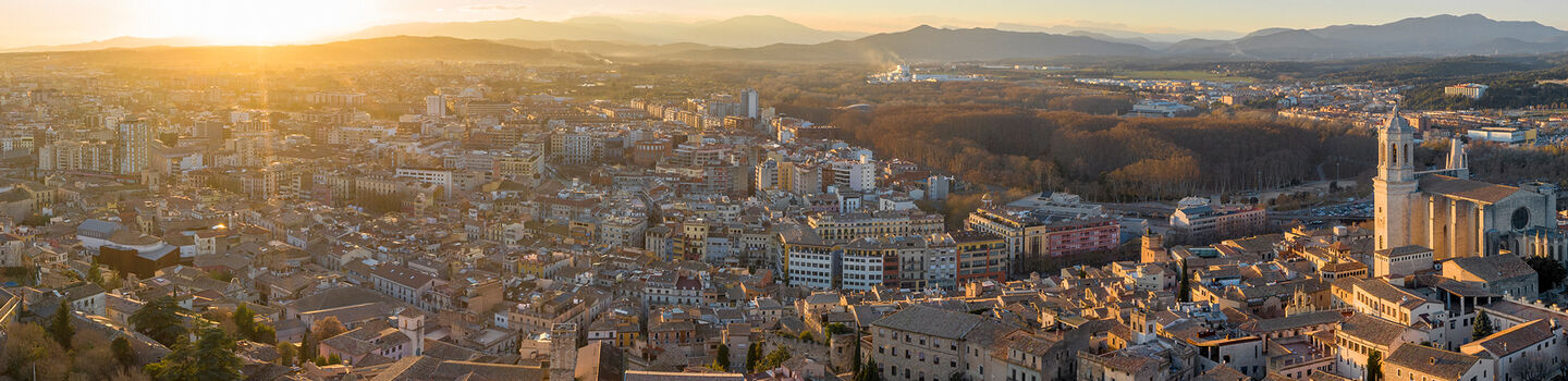 Vom hohen Standpunkt aus präsentiert sich Girona als ein Meer aus Dächern, das im warmen Licht der hinter dem Horizont versinkenden Abendsonne schimmert.