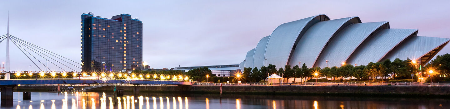 Das imposante Scottish Exhibition Centre in Glasgow prägt das Stadtbild, flankiert vom ruhigen Fluss und einer eleganten Brücke.