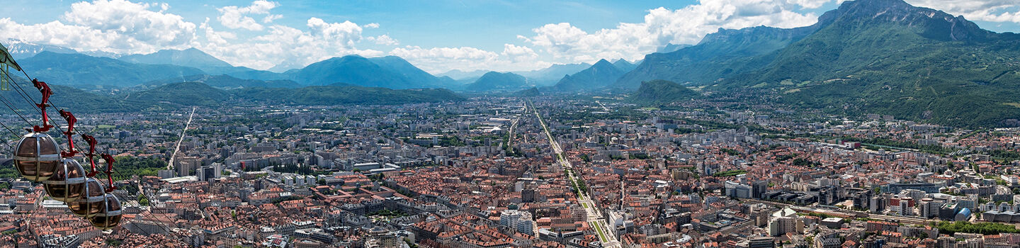 Panoramablick auf Grenoble mit der ikonischen Seilbahn zum Fort de la Bastille und den Alpen im Hintergrund