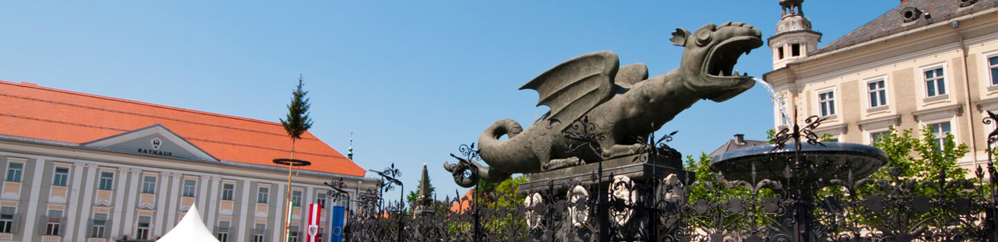 Im Zentrum von Klagenfurt zieht der Lindwurm auf dem Neuen Platz die Blicke auf sich, umgeben von historischen Gebäuden.