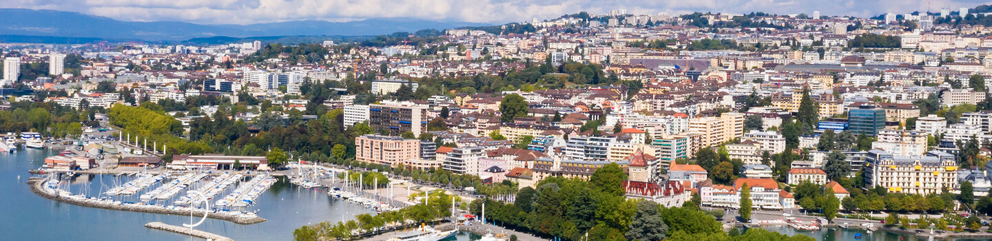 In der Luftaufnahme von Lausanne formen die dichten Gebäude ein beeindruckendes Stadtbild, das bis zum See reicht.
