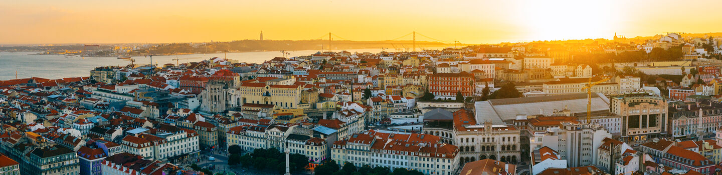 Der Panoramablick auf Lissabon entfaltet eine atemberaubende Szenerie, wo die weißen Gebäude und roten Dächer gegen den sonnigen Abendhimmel kontrastieren.