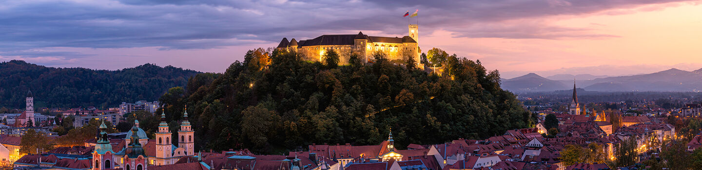 Im Zentrum der Altstadt von Ljubljana erhebt sich das Schloss majestätisch über der Stadt und erstrahlt in der Abendstimmung, während es die umliegende Landschaft überschaut.