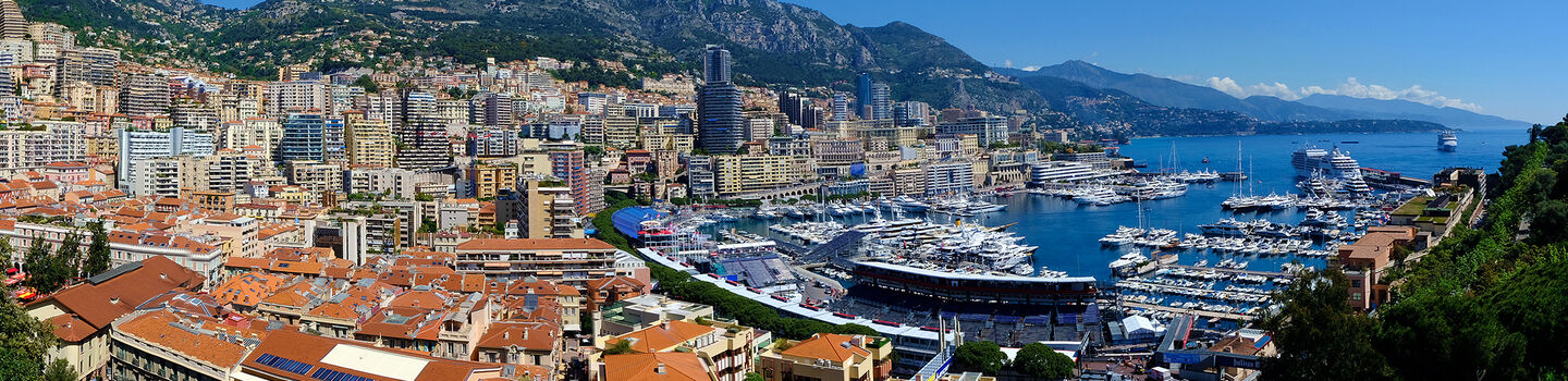 Im Panorama von Monaco zeichnen sich die luxuriösen Hochhäuser entlang der Hügel ab, während der Hafen mit seinen zahlreichen Jachten zu ihren Füßen liegt.