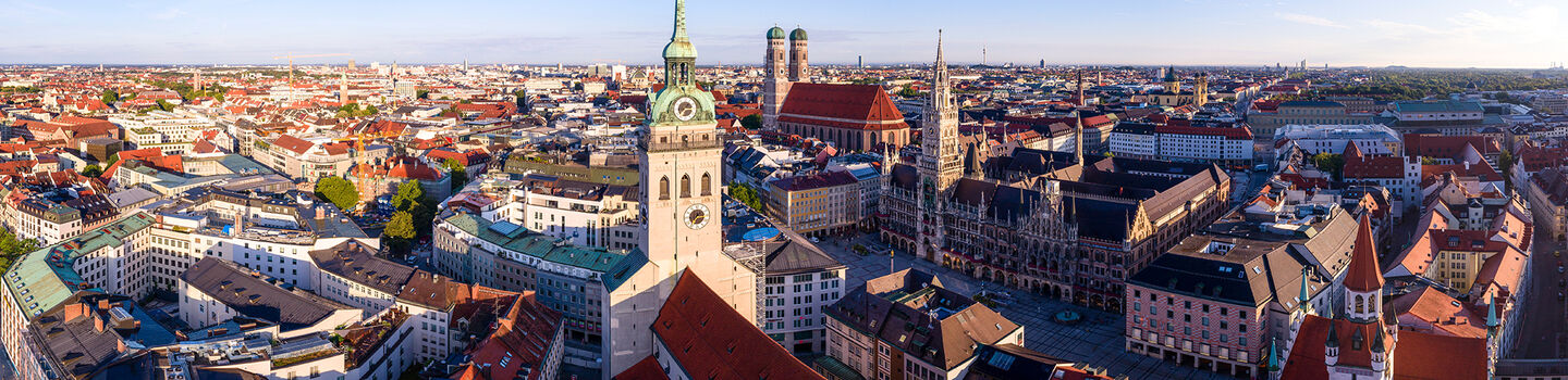  Luftaufnahme von München, mit den Dächern der Stadt, die sich unter einem blauen Himmel erstrecken.