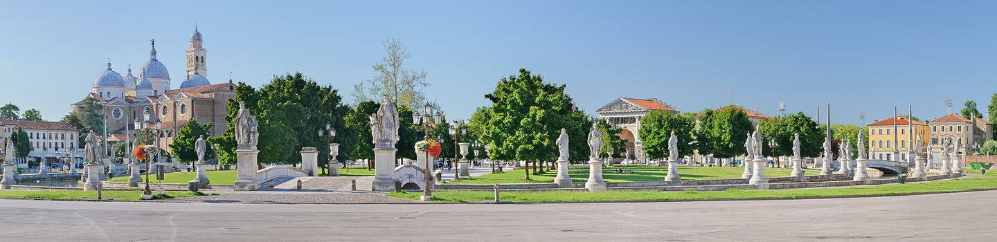 Ein Blick auf den Prato della Valle in Padua, mit den weißen Statuen auf dem Platz und den umgebenden Gebäuden im Hintergrund.