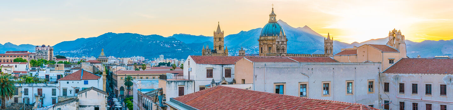 Palermo bei Sonnenuntergang, mit den historischen Gebäuden und den kühlen, blauen und grauen Tönen des Himmels, die die Stadt umhüllen.