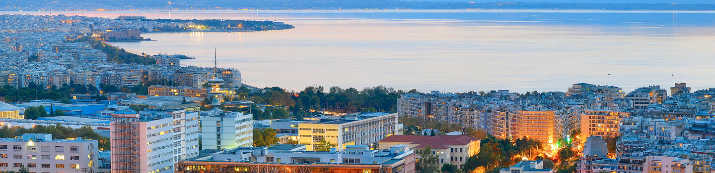 Bei abendlicher Dämmerung erstrahlt Thessaloniki von oben betrachtet in einem sanften blauen Schimmer.