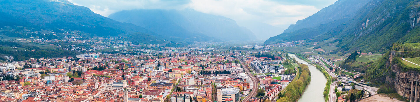 Die Stadt Trento, eingebettet in die malerische Landschaft Italiens, mit der Etsch, die sich sanft durch die Stadt schlängelt.