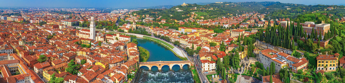 Die Stadt Verona mit ihren historischen Gebäuden und dem ruhig fließenden Fluss Etsch, der sich durch die Stadt zieht.