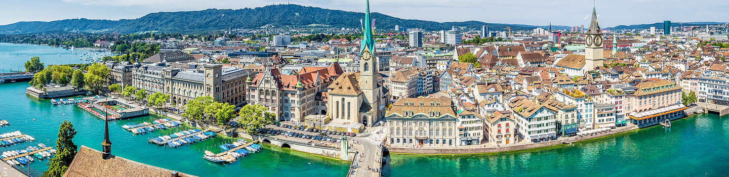 Im warmen Sommerlicht präsentiert sich Zürich mit seinem glitzernden See und den charakteristischen Gebäuden, die ein malerisches Stadtbild formen