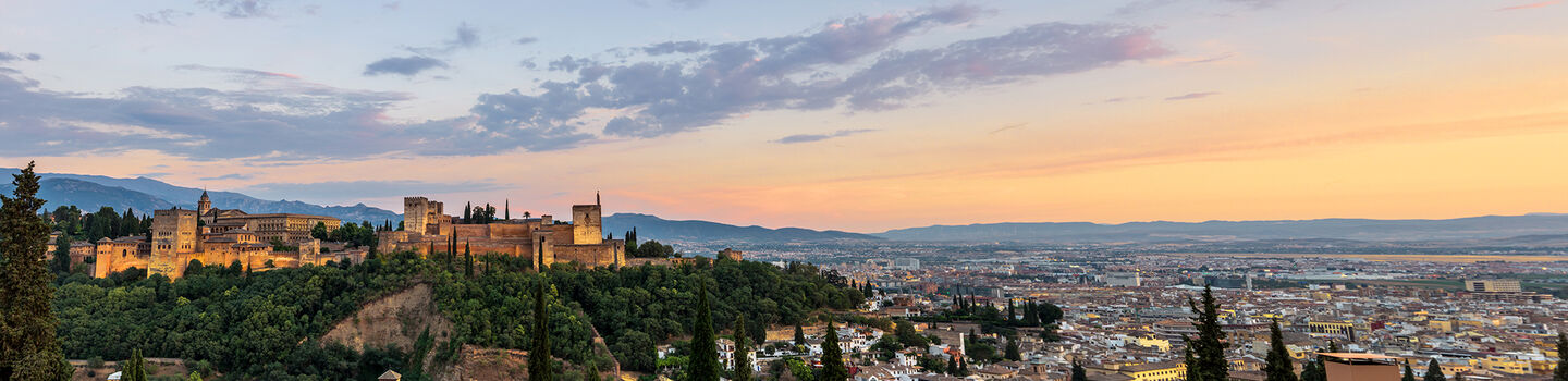 In der warmen Abendsonne wirkt die Alhambra, die über der Stadt Granada thront, noch eindrucksvoller, umgeben von den schimmernden Häusern der Stadt.