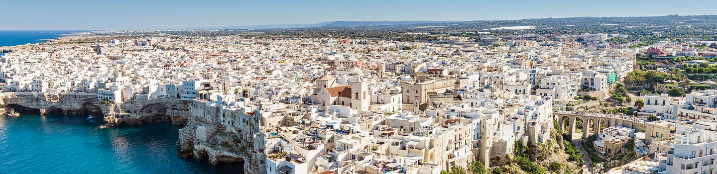 Die malerische Stadt Polignano a Mare mit ihren weißen Häusern thront auf steilen Klippen über dem funkelnden, tiefblauen Meer in Apulien.