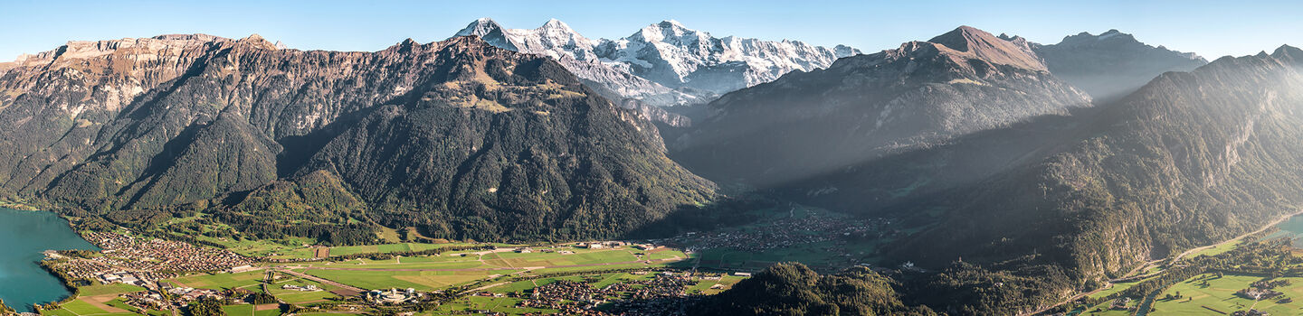 Beeindruckendes Panorama mit den sanften Hügeln des Berner Lands, den majestätischen Alpengipfeln im Hintergrund und den ruhigen Seen zu beiden Seiten.