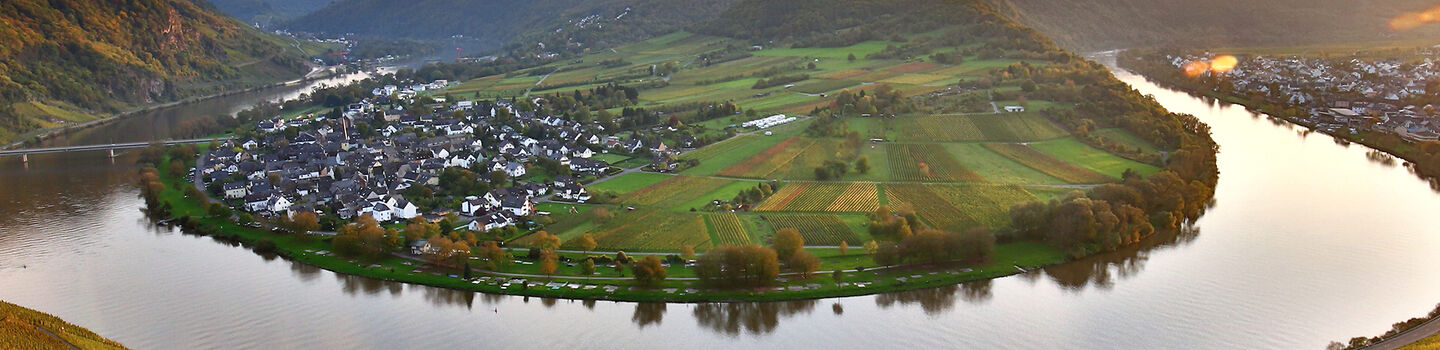 onauschleife im farbenfrohen Herbst, mit goldenen und roten Laubfarben, die sich entlang des Flusses schlängeln, umgeben von sanften Hügeln.