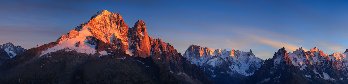 Panoramablick auf die Alpen bei Sonnenuntergang, mit schneebedeckten Gipfeln und warmen Farbtönen