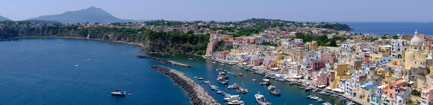 Die Insel Procida im Golf von Neapel, mit ihren bunten Häusern, die sich entlang der Küste erstrecken, umgeben von weiten, tiefblauen Meer.