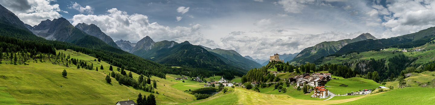 Das Panorama des Unterengadins bei Tarasp offenbart eine Landschaft von atemberaubender Schönheit, mit sanften Tälern und Bergen, die sich bis zum Horizont erstrecken.